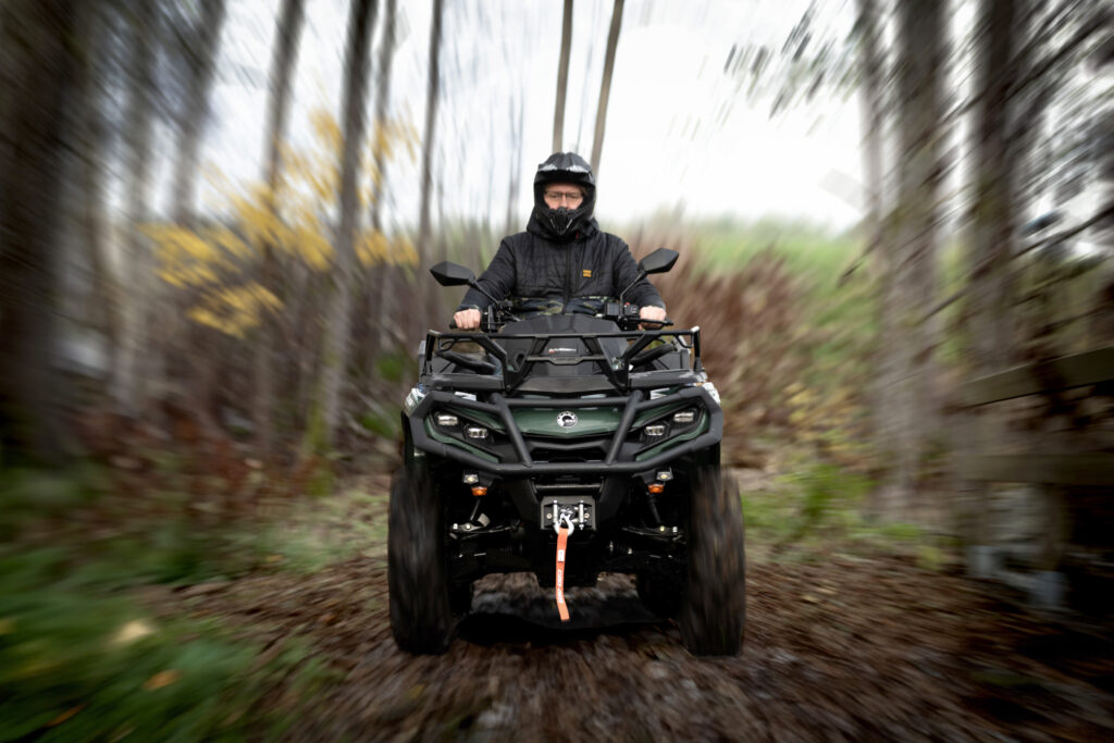 Can-Am fyrhjuling i rörelse i skogsmiljö – optimal för skogsägare och jägare.